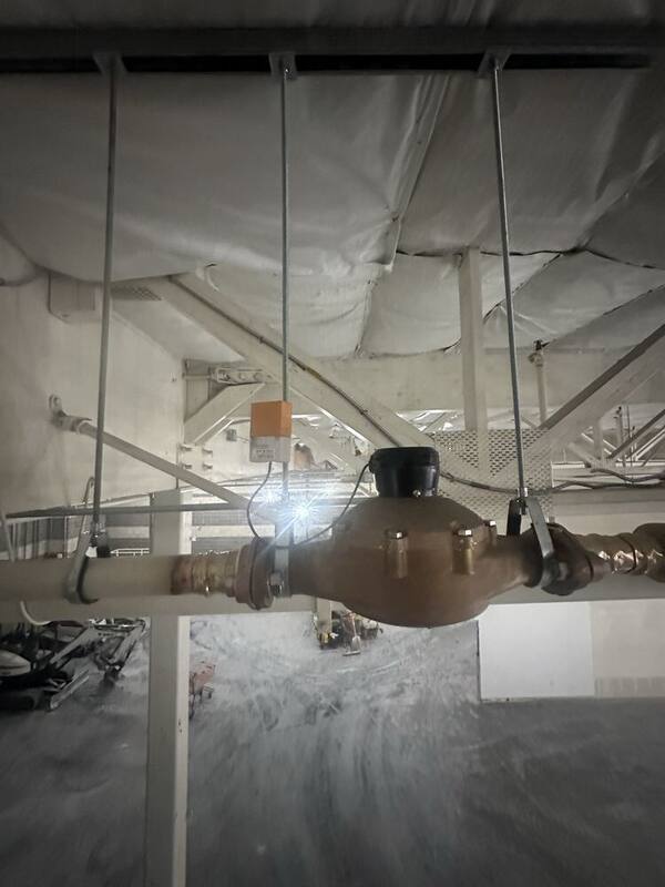 Commercial water meter and backflow prevention assembly installed on overhead piping in a commercial building
