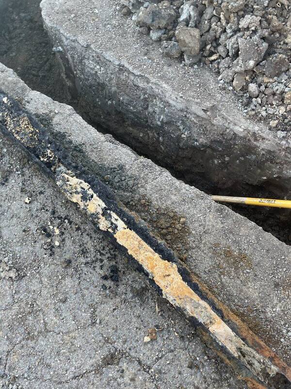 Excavated trench exposing a corroded main water line ready for replacement