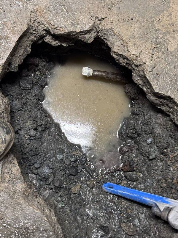 Plumber repairing a corroded pipe leak with a pipe repair clamp