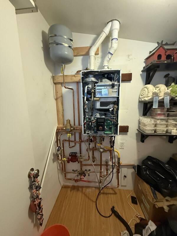 Tankless water heater professionally installed with copper piping and expansion tank in a Salt Lake City utility closet